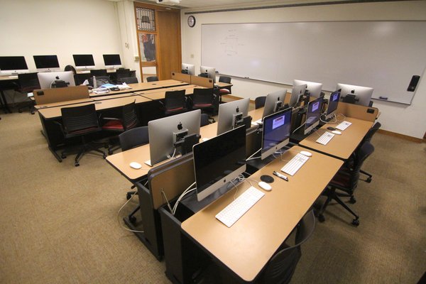 4排桌子和电脑在可伸缩臂上，2块大白板固定在墙上，一个教学讲台放置在白板的一侧。