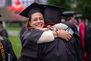 穿着毕业袍和毕业帽的学生拥抱人
