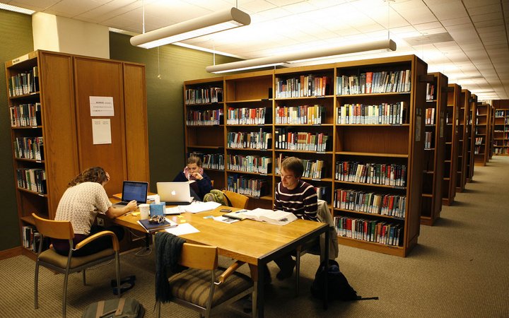 学生们坐在书架旁的桌子旁