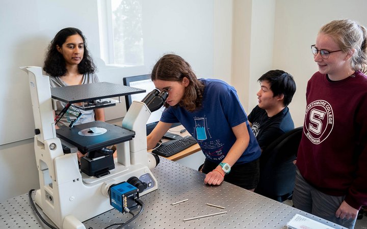 学生通过显微镜观察，3名学生观察