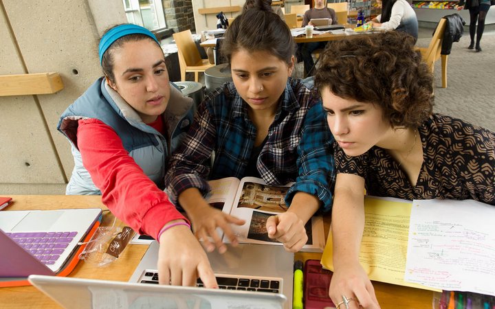 三个学生看着笔记本电脑
