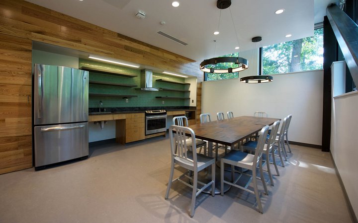 厨房空间，桌子在房间的中间，大的金属冰箱在左边。