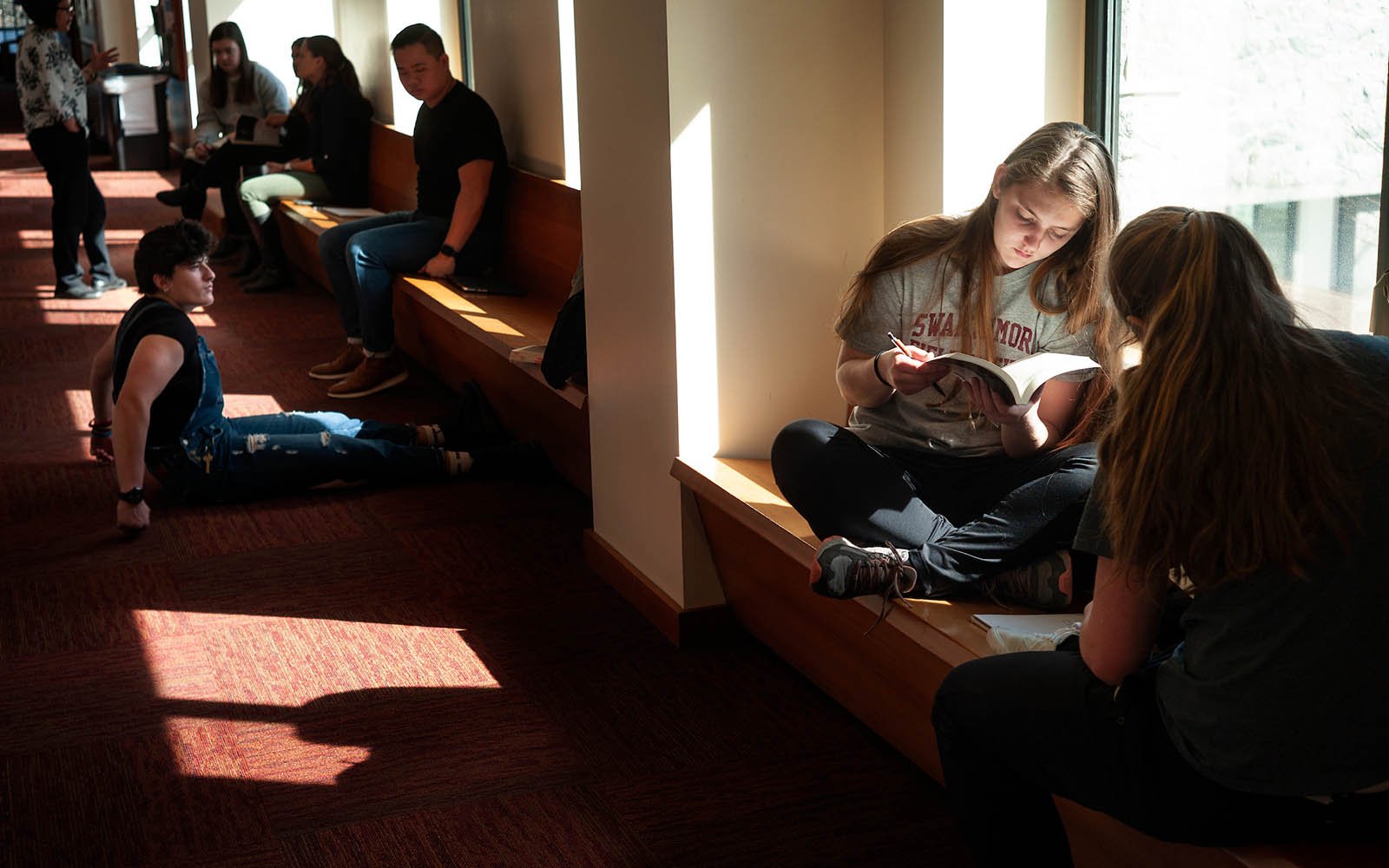 学生阅读和躺在一个窗口的走廊内Kohlberg大厅