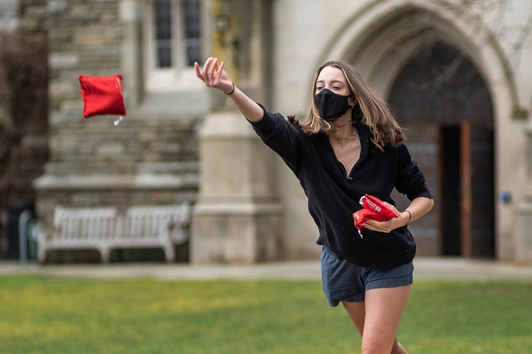 戴口罩的学生将红豆袋扔到户外。