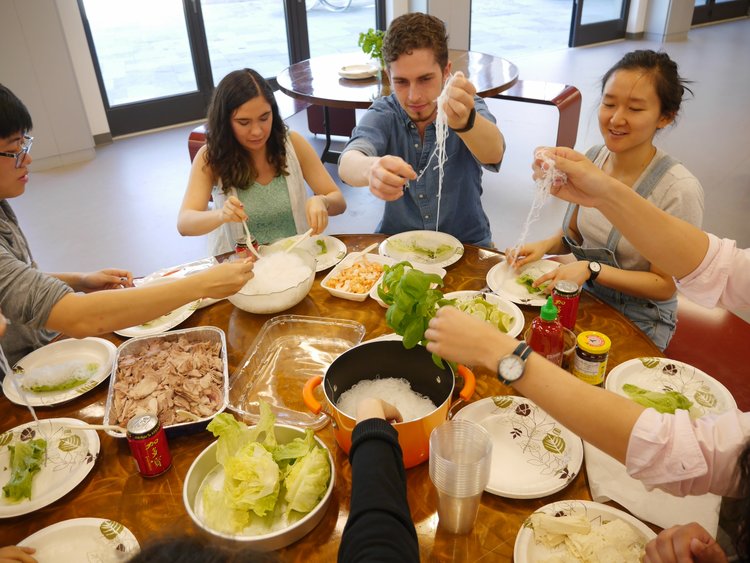 一群学生享受似乎是越南粉丝面条和一些绿叶蔬菜组成的饭菜